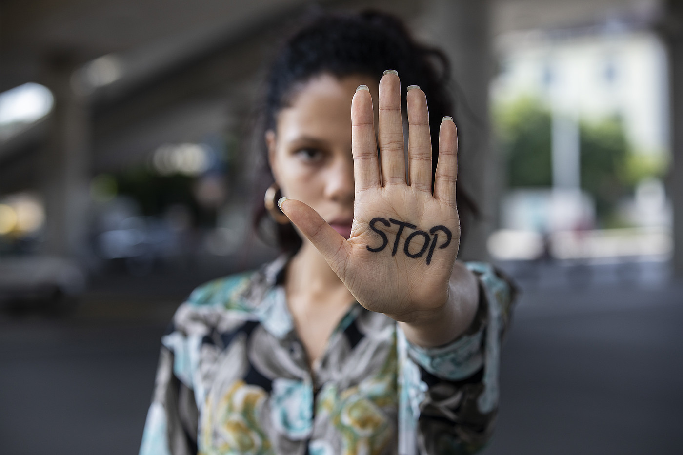 Eine junge Frau streckt ihre Hand aus. Darauf steht STOP.